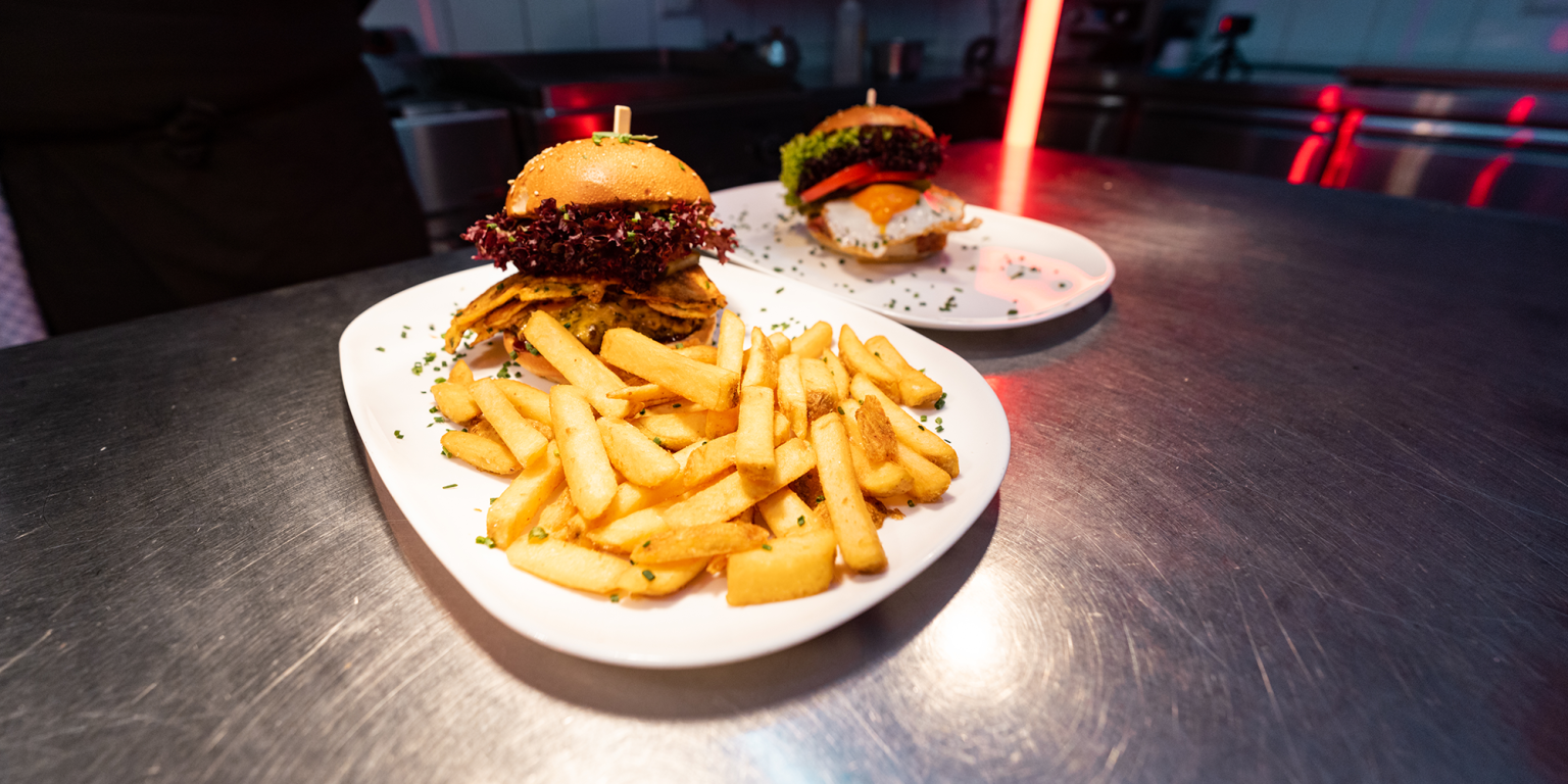 Ein Bild von einem köstlichen Burger mit Pommes, fotografiert während eines Food-Fotoshootings für Tommy's Braterei. Hochauflösende Fotografie für Social Media von JNPhotografics.