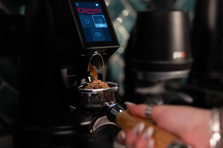 Kaffeemühle mahlt frisch geröstete Kaffeebohnen in einen Siebträger – professionelle Fotoaufnahme für Gastronomie-Marketing und B2B-Inhalte, geeignet für Restaurant- und Café-Betreiber, die hochwertige Foto- und Videoproduktion suchen.