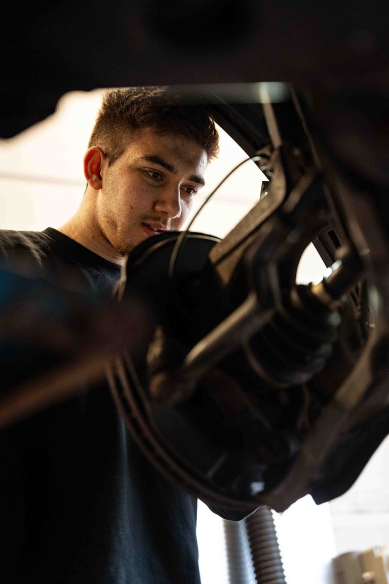Mitarbeiter in der KFZ-Werkstatt bei der Reparatur – professionelle Mitarbeiterfotografie
