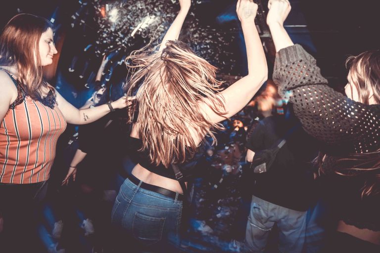 Festivalbesucher tanzen und feiern unter den bunten Lichtern bei einem Techno-Festival