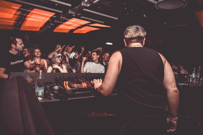 Menge tanzt und feiert auf dem Techno-Festival unter den spektakulären Lichtern