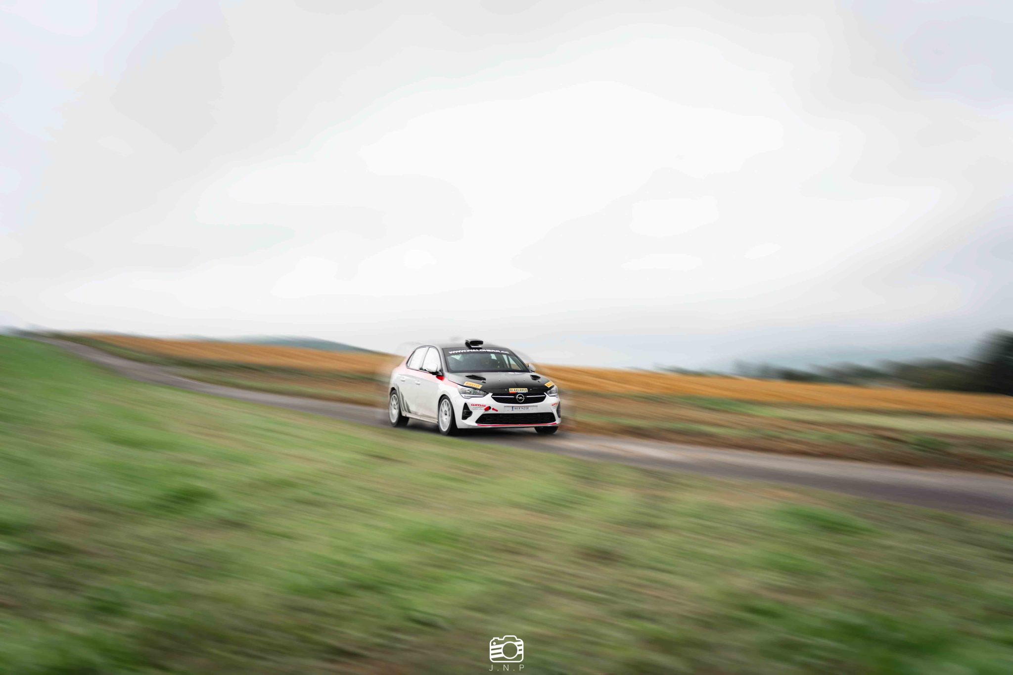 Dynamische Contentproduktion im Motorsport: Mitzieher-Aufnahme eines Rallyeautos bei hoher Geschwindigkeit – JNPhotografics.