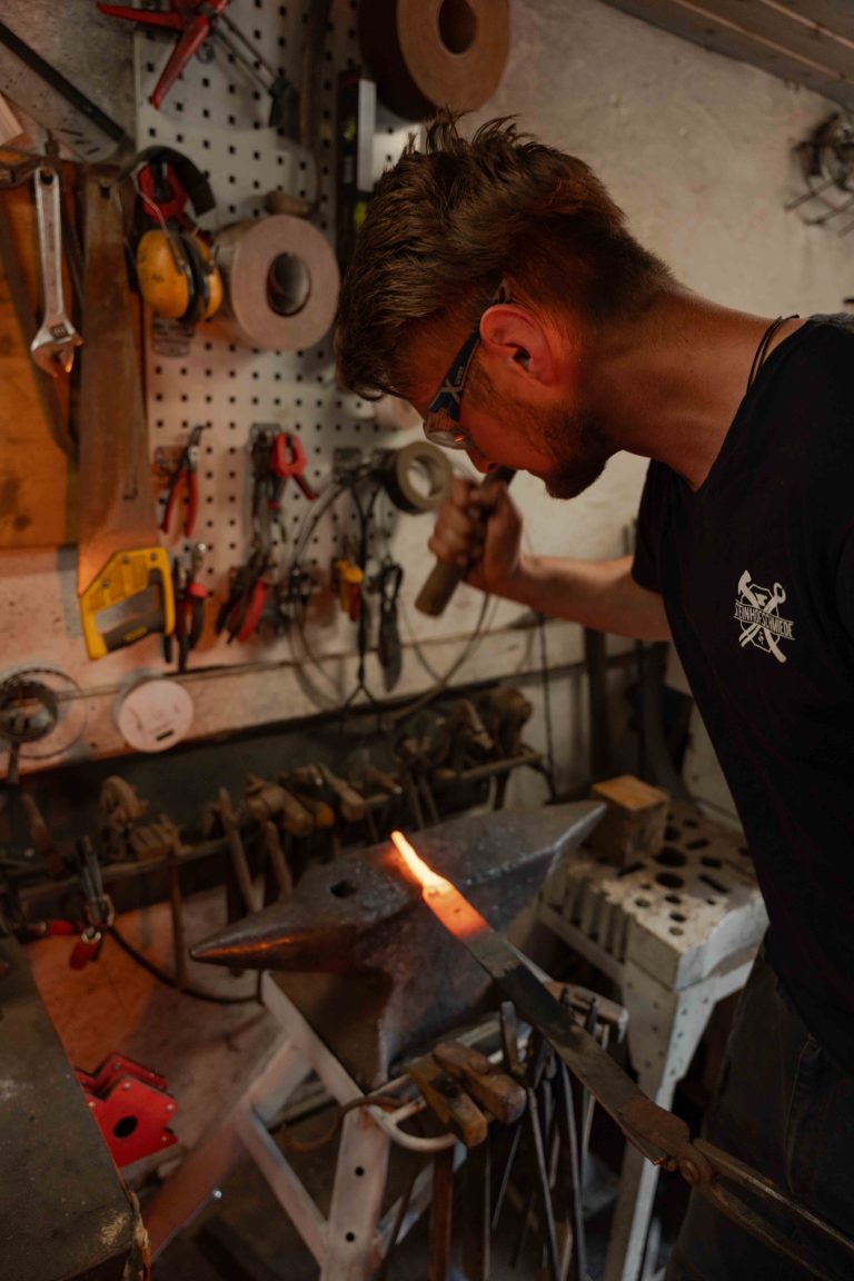 Justus Tillmann beim Messerschmieden in der Steinhofschmiede mit Feuer und glühendem Metall am Amboss.