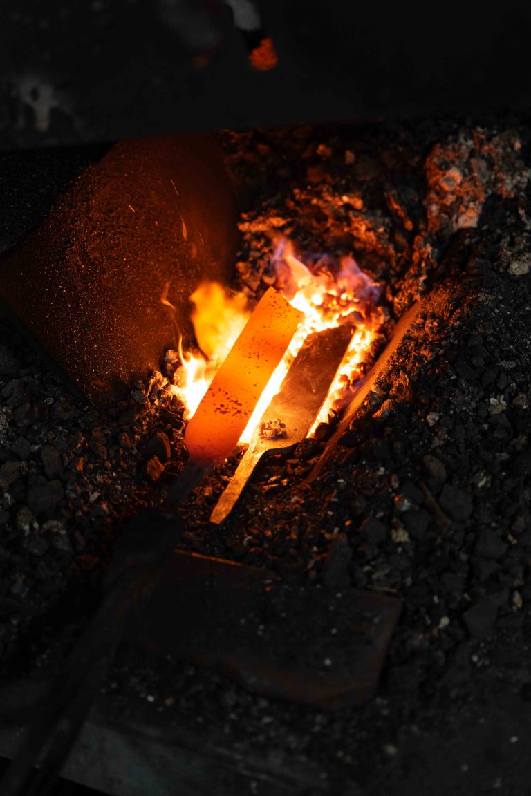 Imagefotografie in der Steinhofschmiede mit Messerschmied bei der Arbeit am Amboss und glühendem Metall im Schmiedefeuer.